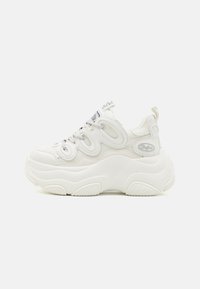 White chunky sneakers featuring a mesh and synthetic upper, curved shape, textured sole, and prominent lacing system with logo details.