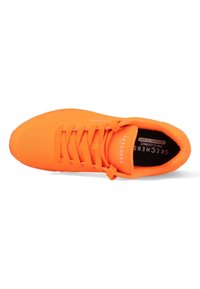 Scarpa atletica arancione brillante con una tomaia sintetica liscia, texture perforata per la traspirabilità e lacci piatti. Presenta una soletta nera.