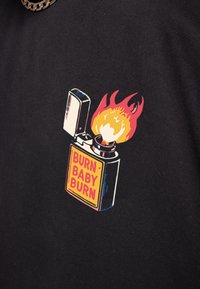 Camiseta negra con un gráfico de un encendedor con llamas y el texto "BURN BABY BURN" en amarillo y rojo, impresa en suave tela de algodón.