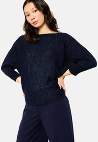 Navy blue knit sweater with a relaxed fit, boat neckline, and short sleeves. Features a subtle sparkling texture throughout.
