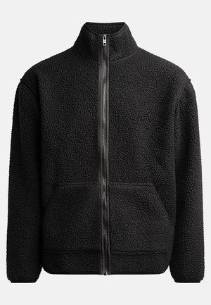 Chaqueta de forro polar negra con cuello alto, cremallera frontal completa, dos bolsillos laterales, tejido texturizado y ribete negro en los puños y el dobladillo.