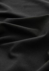 Tessuto nero con una texture liscia, caratterizzato da pieghe e drappeggi sottili, che evidenziano il suo materiale leggero e flessibile.