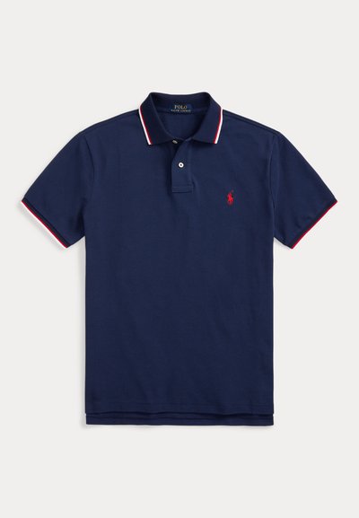 Camisa polo azul marinho em algodão, com um colarinho listrado em vermelho e branco, com três botões e um pequeno logotipo bordado no peito.