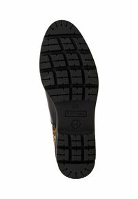 Semelle en caoutchouc noire avec motif de bande de roulement profond sur une chaussure à imprimé léopard, affichant le nom de la marque et la taille 37.