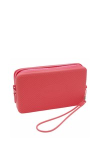 Portafoglio rettangolare in corallo realizzato in gomma testurizzata, con chiusura a zip, tracolla e logo "havaianas" in rilievo sul davanti.