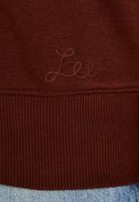 Sudadera burdeos con dobladillos y puños acanalados, con el logotipo 'Lee' bordado en un hilo contrastante. Tejido suave y texturizado.