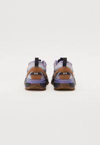 Brune og lilla sneakers med en teksturert semsket overdel, mesh-detaljer og en kraftig svart såle. Har strikker på hælen for enkel påkledning.