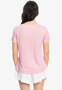 Kortærmet lyserød T-shirt lavet af blødt stof, med rund halsudskæring og afslappet pasform, parret med hvide shorts.