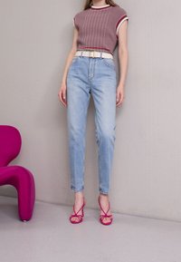 Tajt ribbad rosa topp med vit kant, högmidjade ljusblå jeans, vit bälte och rosa remsandaler. Släta, solida texturer.