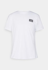 Camiseta blanca de algodón con cuello redondo, mangas cortas y un parche de logo rectangular negro en el lado izquierdo del pecho. Diseño sencillo, tejido ligero.