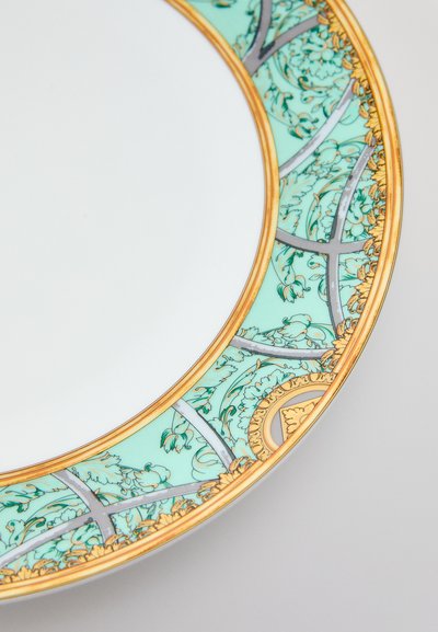 Στρογγυλό πορσελάνινο πιάτο με τυρκουάζ και χρυσό ανθισμένο περίγραμμα, που διαθέτει περίπλοκα μοτίβα και γυαλιστερή λευκή εσωτερική επιφάνεια.