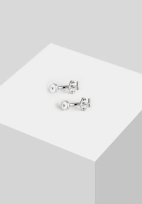Silverfärgad manschettknappar med cirkulär design som har en stjärnformad accent, polerad yta och en enkel, elegant clasp-mekanism.
