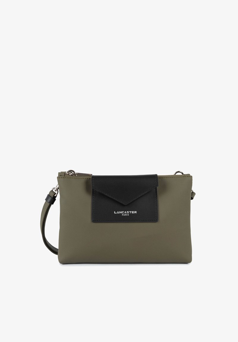 Sac à main en vert olive en matériau texturé, avec un rabat en cuir noir et des détails en argent, doté d'une bandoulière ajustable.