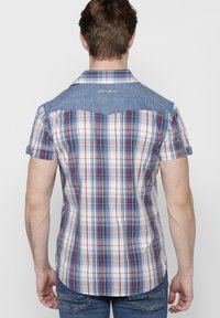 Camicia a maniche corte a quadri con yoke di denim nei colori blu, rosso e bianco, con un sottile dettaglio ricamato sul retro.