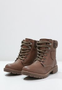 Hnědé kožené kotníkové boty z umělé kůže s texturovaným povrchem, vybavené pevným šněrováním, kovovými očky a akcentem z umělé kožešiny na límci.