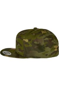Căciulă cu model camuflaj în nuanțe de verde și marron, având o vârful plat și o coroană rotundă cu un finisaj din țesătură texturată.