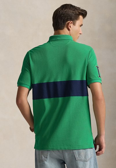 Πράσινο πουκάμισο πόλο με οριζόντια ναυτική ρίγα στο πίσω μέρος. Κοντά μανίκια, υφασμάτινη υφή και κλασικός γιακάς.