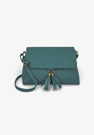 Sac bandoulière en cuir bleu sarcelle avec une sangle ajustable et deux décorations à pompons suspendues à un anneau doré sur le rabat avant.