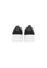 Zapatillas negras con una parte superior lisa y brillante y acentos de tela texturizada. Suelas de goma blanca con ligera elevación y marca en relieve en el talón.