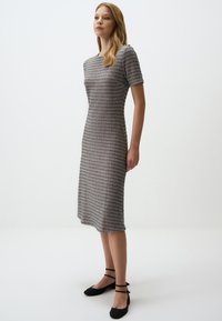 Robe grise à motif avec des manches courtes, coupe droite et longueur au genou. Elle présente un tissu tricoté texturé et un décolleté simple.