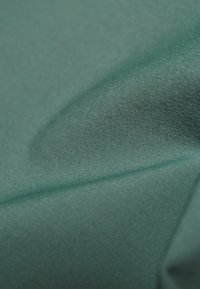 Tissu bleu sarcelle lisse avec de légers plis et une texture subtile visible à la surface.