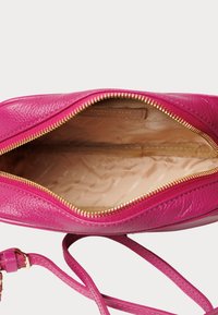 Borsa a mano in pelle rosa con apertura con zip, texture liscia e interno beige con un motivo sottile. Inclusa una lunga tracolla regolabile.