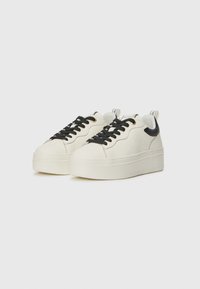 Sneaker platform bianchi con lacci neri e accentuazione sul tallone, materiale in pelle liscia, punta rotonda e dettagli testurizzati sui lati.