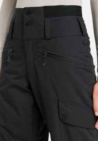 Black snow pants with a high waistband, two front zippered pockets, and a cargo pocket on the side. Made of a durable, textured fabric.