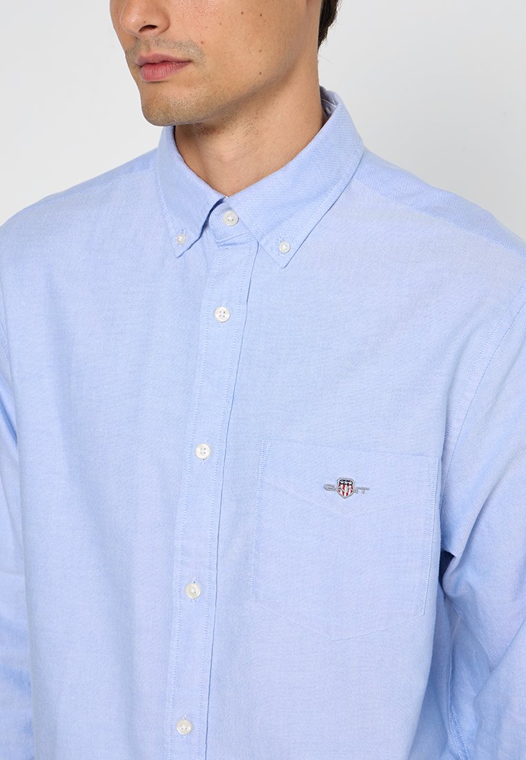 Jasnoniebieska, zapinana na guziki koszula wykonana z bawełny. Posiada strzałkowy kołnierz, długie rękawy oraz przednią kieszeń z akcentem w postaci logo.