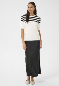 Tricou tricotat cu maneci scurte, alb și negru cu dungi, asortat cu o fustă lungă neagră, însoțit de balerini de culoare deschisă. Texturi fine și design clasic.