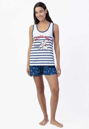 Mujer sonriente con camiseta de tirantes blanca con rayas azules con el texto "Bonne Nuit" y un gráfico de gato, combinada con pantalones cortos azules con pequeños estampados de gatos.