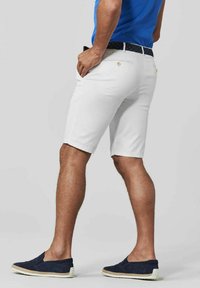 Witte shorts met een gladde textuur, met zijzakken en een blauw patroon op de riem. Gedragen met marineblauwe instappers.