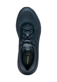 Zapatilla deportiva azul oscura con una superficie de cuero suave, cuello acolchado y cordones elásticos. Presenta una suela texturizada y un logotipo en el interior.