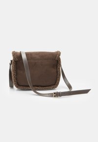 Borsa a tracolla in suede marrone con un bordo in pelliccia testurizzata e una tracolla in pelle regolabile. Forma quadrata con chiusura a patta. Dettagli in metallo dorato.