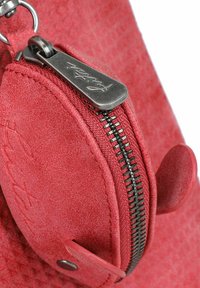 Rode suède tas met een ritsvak, zilveren hardware en textuurdetails. Opvallende ronde accenten en zichtbare gladde stiksels.