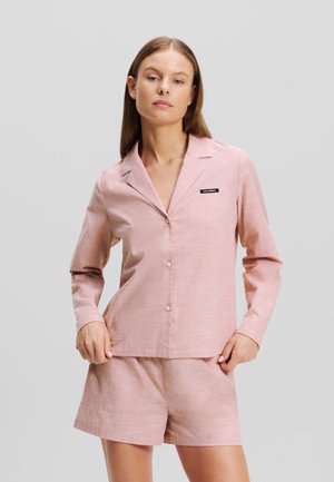 Light pink pajama set featuring a button-up top with long sleeves and matching shorts. Material has a subtle texture; includes a small branding label.