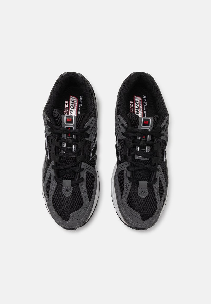 Zapatillas deportivas negras con parte superior de malla, con acentos grises, suela texturizada y diseño de cordones. Logo en la lengüeta y el lateral.