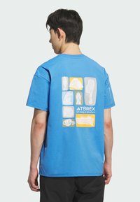 T-shirt in cotone blu con stampa grafica sul retro con illustrazioni a tema avventura in giallo e grigio. Maniche corte, colletto rotondo.