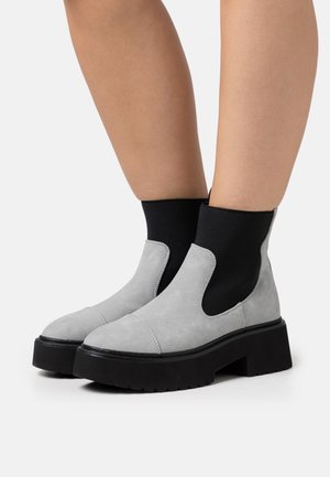 Stivaletti alla caviglia in camoscio grigio con inserto elastico nero, suola piattaforma spessa nera e punta arrotondata. Tessuto piatto con dettagli di cucitura.