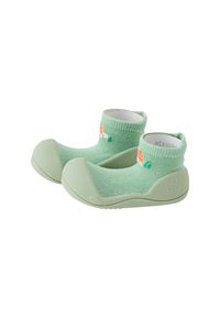 Zapatos blandos verdes para niños pequeños con parte superior de punto tipo calcetín, suelas de goma y un pequeño diseño naranja y blanco cerca del tobillo.