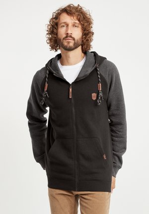 Crna i siva zip-up hoodie s kapuljačom na vezivanje, prednjim džepovima i teksturiranim materijalom. Sadrži zakovicu s logotipom na prsima i akcentne detalje.