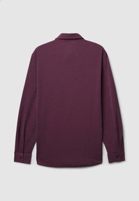 Langärmliges Hemd aus tiefviolettem Stoff mit strukturierter Oberfläche. Es verfügt über einen umgeschlagenen Kragen und geknöpfte Manschetten. Schlichtes, sauberes Design.