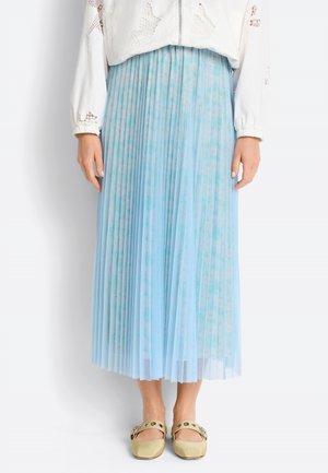 Mid-length pleated light blue floral skirt worn with a white lace long-sleeve top and beige flat shoes with buckles.