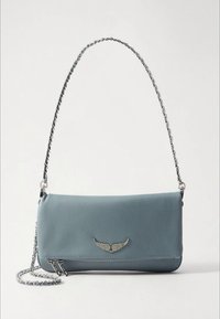 Borsa a mano in pelle blu con tracolla a catena argentata, caratterizzata da un emblema decorativo a forma di ala e design elegante, chiusura superiore e dettaglio di tasca con cerniera.