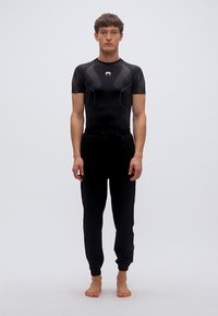 Μαύρο αθλητικό κοντομάνικο μπλουζάκι συμπίεσης με υφή, συνδυασμένο με μαύρο παντελόνι jogger με ελαστική μέση.