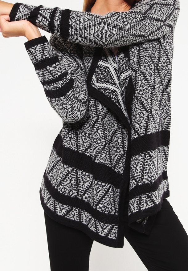 Svart- och vitt mönstrad cardigan med en texturerad stickning, öppet front och långa ärmar. Har en geometrisk design och kontrasterande ränder.