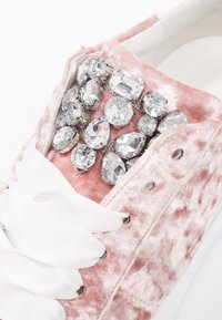 Baskets roses en velours ornées d'un bouquet de strass transparents sur le dessus, avec des lacets en satin blanc et une surface texturée.