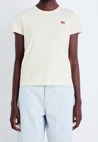 Jasnożółta koszulka w paski z okrągłym dekoltem i krótkimi rękawami, z małym czerwonym logo Levi's na lewej piersi.