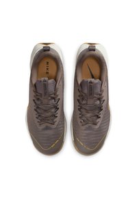 Brown athletic shoes with mesh upper, textured laces, and a light-colored sole. Features a logo and branding on the tongue and side.