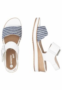 Sandales compensées blanches avec une bande en tissu à motif zigzag bleu marine. Bride réglable à la cheville et semelle en caoutchouc texturé pour une meilleure adhérence.